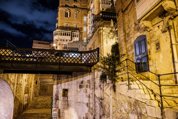 the empty streets of Valletta at night. Street lights illuminate the old houses
