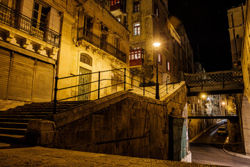 the empty streets of Valletta at night. Street lights illuminate the old houses