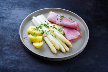 Traditional steamed white asparagus with juniper ham and boiled potato in hollandaise sauce served...