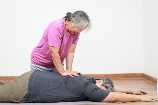 Elderly Asian masseuse doing back massage for fat man lying on the floor. Physical therapy. healthy massage concept