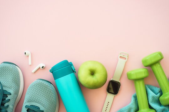 Workout, healthy lifestyle concept. Sneakers, dumbbells, green apple and bottle of water. Flat lay with copy space.