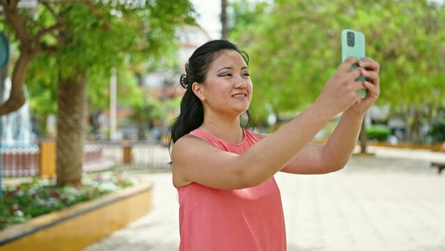 Young chinese woman smiling confident making photo by the smartphone at park