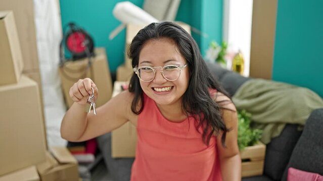 Young chinese woman smiling confident pointing to new house keys at new home