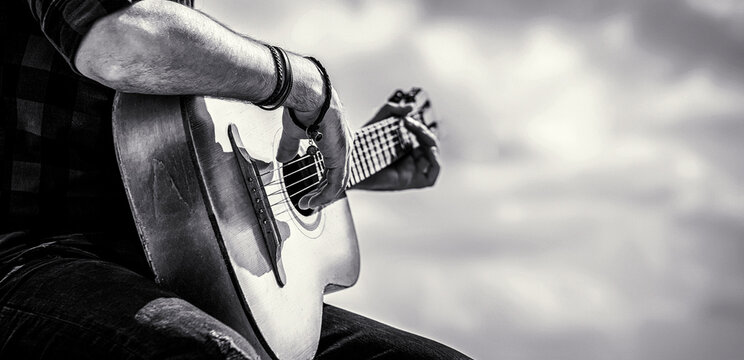 Guitars acoustic. Male musician playing guitar, music instrument. Man's hands playing acoustic guitar, close up. Black and white