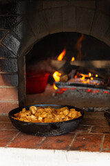 Vegetables languish in a cast-iron frying pan in a Russian oven, ratatouille, a frying pan on a pole