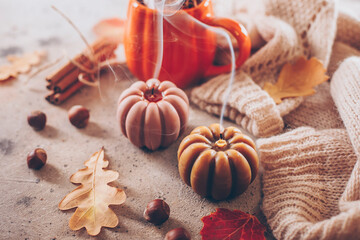 Extinguished candle with smoke, mug with autumn drink, leaves, warm sweater and cinnamon. Halloween holiday concept