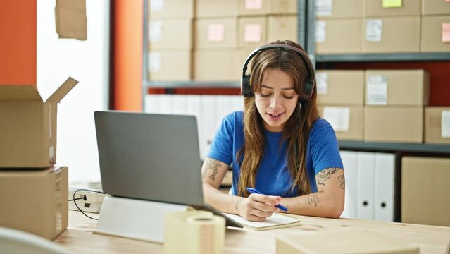 Young beautiful hispanic woman ecommerce business agent on a video call writing on package at office