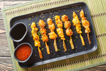 Delicious Japanese-style chicken skewers served with two sauces close-up on a plate on the table....