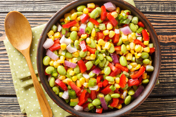 Delicious salad cooked with edamame soybeans, bell peppers, corn, tomatoes and onions close-up in a bowl on the table. Horizontal top view from above
