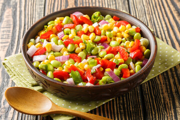 Fresh salad with green soybeans, bell peppers, corn grains, tomatoes and onions close-up in a bowl...