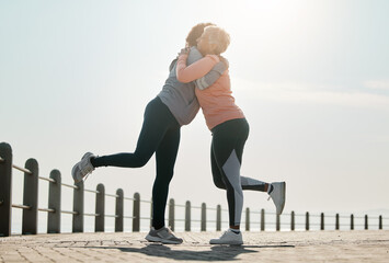 Running, hug and women by sea and ocean with love and care for fitness and exercise. Athlete, wellness and female friends on a beach promenade with motivation, embrace and smile from runner target - obrazy, fototapety, plakaty