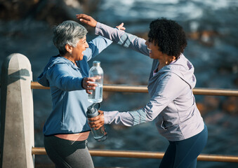 Running, excited hug and women by sea and ocean with love and care for fitness and exercise. Athlete, greeting and mature person with friend on a beach promenade with motivation, embrace and smile © aLListar/peopleimages.com