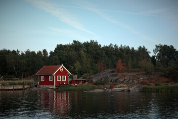 Fototapeta na wymiar red wooden hut in a forest in Sweden by a lake. Peace in nature and ideal place for vacation