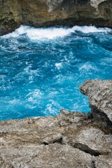 Wild and deep blue water at 'devil's tears' spot at Nusa Ceningan Island, Bali, Indonesia. Wild splashing water at the rough and rocky coastline of Nusa Ceningan Island. Beautiful wild scenery. 