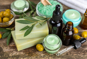 Spa olive. Composition with a jar of natural olive cream, essential oils, sea salt and natural handmade soap with olive and olive sprigs on a brown background. Beauty and relax concept. Flat lay