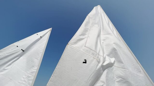 dinghy sail swaying in the wind, blue sky in the background