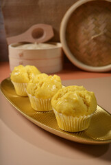 freshly handmade beautiful local nonya teochew pumpkin cup cake, huat kuih on gold colourful Pantone background with wood bamboo decoration halal food asian dessert menu for cafe