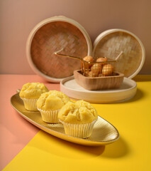 freshly handmade beautiful local nonya teochew pumpkin cup cake, huat kuih on gold colourful Pantone background with wood bamboo decoration halal food asian dessert menu for cafe