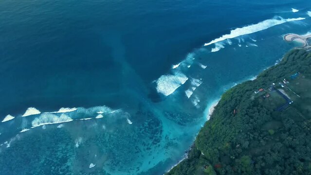 Aerial view of coastline with ocean waves and powerful current canal in Bali.