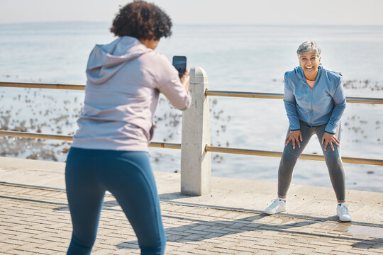 Phone, photograph and friends laugh of senior women at beach with funny joke at sea for fitness. Exercise, mobile and picture for social media post on ocean promenade walk for workout and friendship