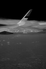 Black and white photo of a plane above the cloud