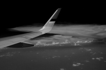 Black and white photo of a plane above the cloud