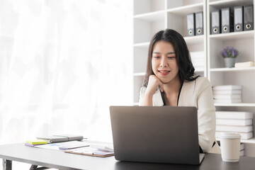 Fototapeta na wymiar Portrait of an Asian businesswoman in a formal suit working with a laptop in a modern office, human resources and small business owner, businessman concept, financial accounting.