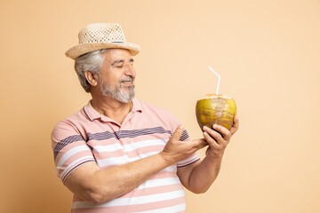 Retired senior indian man casual cloths and hat drinking coconut water while standing isolated on...