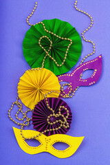 Festive Mardi Gras masquerade violet background. Fat Tuesday carnival, masks, beads, traditional decor