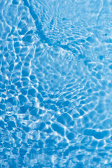 Obraz premium Blue water with ripples on the surface. Defocus blurred transparent blue colored clear calm water surface texture with splashes and bubbles. Water waves with shining pattern texture background.