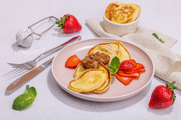 Cottage cheese pancakes, syrniki, curd fritters with strawberry, mint and powdered sugar on plate