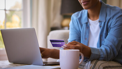 Fototapeta na wymiar Close Up Of Woman At Home With Laptop Using Credit Card To Make Online Purchase Or Book Tickets