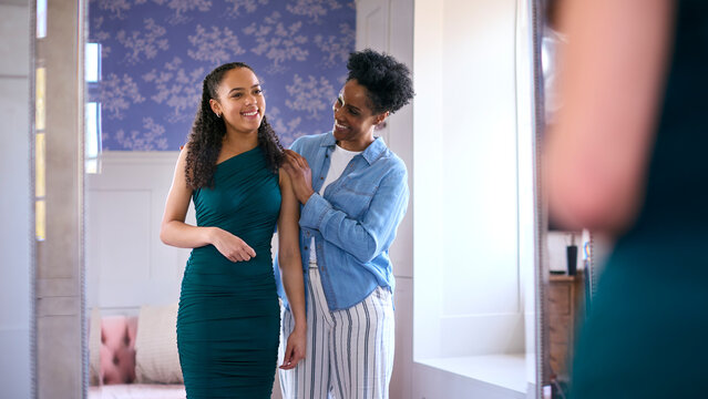 Mother Helping Teenage Daughter In Bedroom At Home Getting Ready For Prom Or Night Out