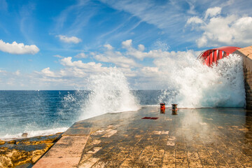 The surf splashes against the St Elmo Breakwater and the spray whips up to the St Elmo Bridge