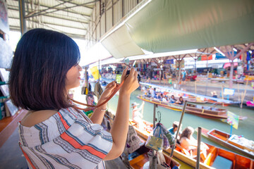 Beautiful tourost woman travel in floating market take photo at Amphawa is a very popular floating...