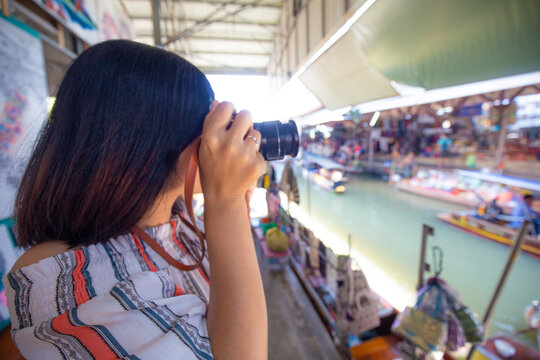 Beautiful tourost woman travel in floating market take photo at Amphawa is a very popular floating market