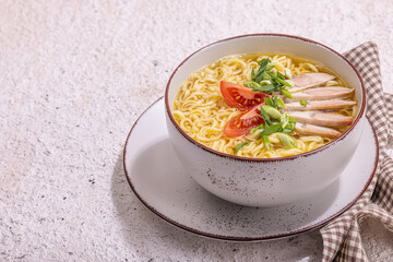 Spicy noodles with beef broth. Hot dish, cutlery, hard light, dark shadow. Stone concrete background