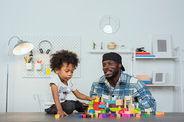 Black father watching his children Play jigsaw puzzles, A boy playing plastic jigsaw puzzles to promote age-related development, learning skills with learning materials to develop children's learning.