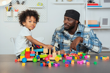 black father teaching his son how to read and watching his children play jigsaw puzzles to enhance learning skills with educational materials for kids. enhancing learning skills learning materials.