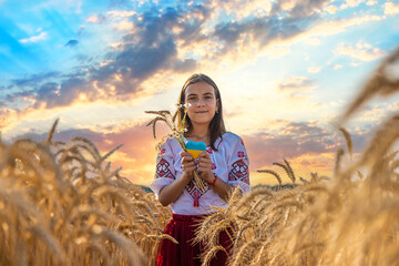 Child in a field of wheat with the flag of Ukraine. Selective focus.