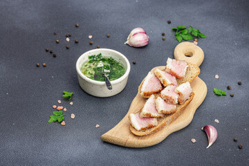 Canapes with rye bread and pieces of salty high-fat meat cooked with spices. Garlic sauce, snack