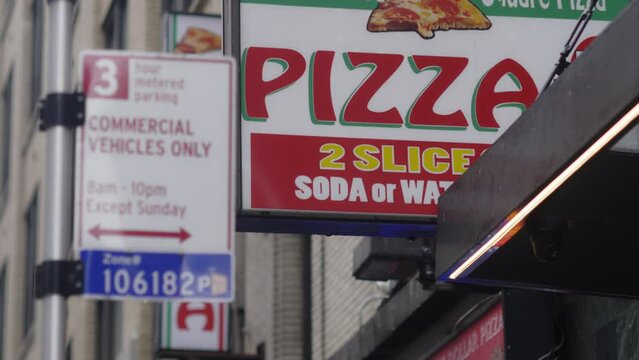 Manhattan signage indicates a nearby pizzeria and parking rules