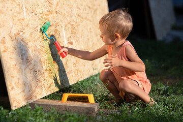 A little boy paints the wall with a roller.The boy plays a builder-painter.A child is holding a...