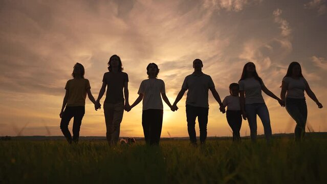 community big family in the park. large sunset group of lifestyle people holding hands walking silhouette nature in the park. big family childhood dream concept. people in the park. big family