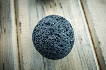 Close up macro shot of a perfectly round black lava stone from the canary island of Fuerteventura. Porous, textured material. Nature's expression.