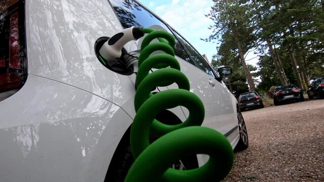 The driver of the electric car inserts the electrical connector to charge the batteries.