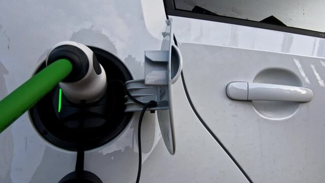 The driver of the electric car inserts the electrical connector to charge the batteries. close up of the plug