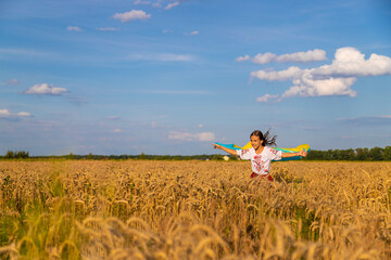 Fototapeta na wymiar Child in a field of wheat with the flag of Ukraine. Selective focus.