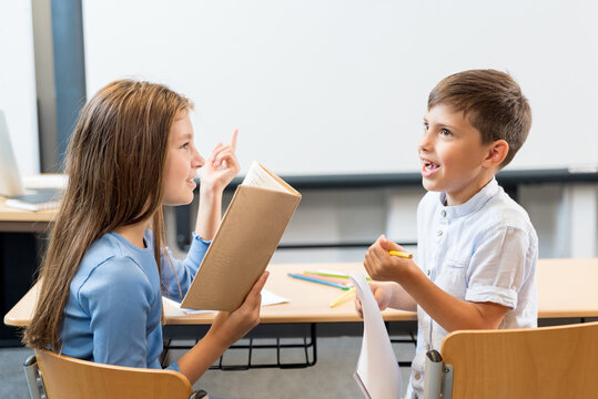 Portrait of two schoolchildren a boy and a girl who are discussing homework, counting aloud and reading write down the subject. The girl as a teacher asks a question the boy answers joyfully