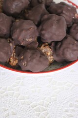 Homemade candy made from nuts and dried fruits. Some are covered in chocolate. They lie on a plate.